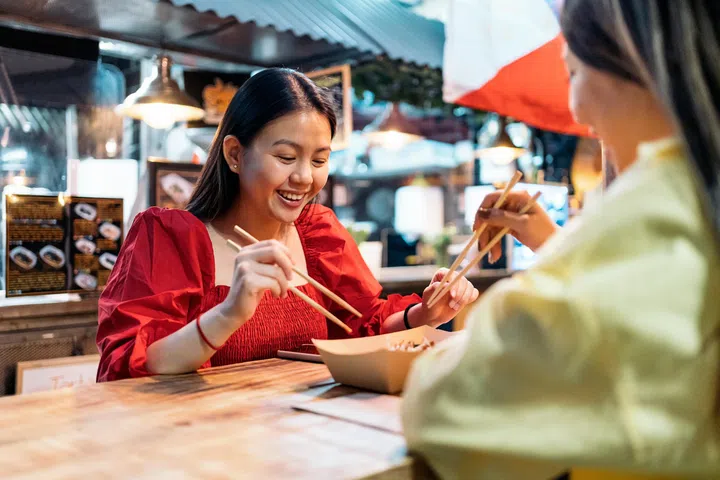 Happy asian female friends sitting in chinese restaurant and enjoying their food.