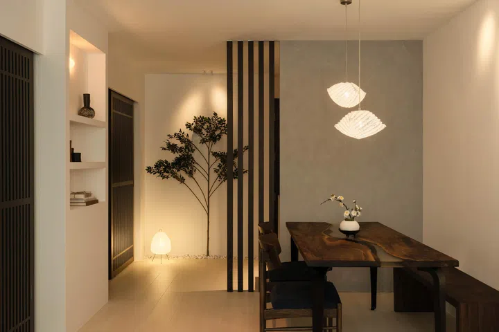  The walnut resin dining table defines the living and dining area, with pendant lights and slatted details completing the Japandi-inspired setting.
