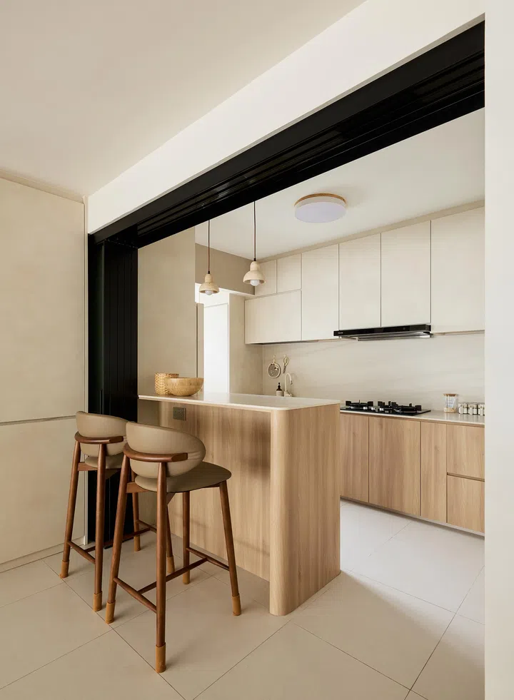 The kitchen’s light wood cabinetry and matte tiles create a warm, clutter-free backdrop.