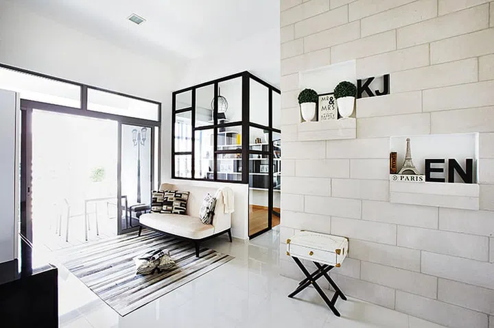 The austere palette of black and white is tempered with rough concrete bricks, a velvet sofa and faux fur patchwork rug.