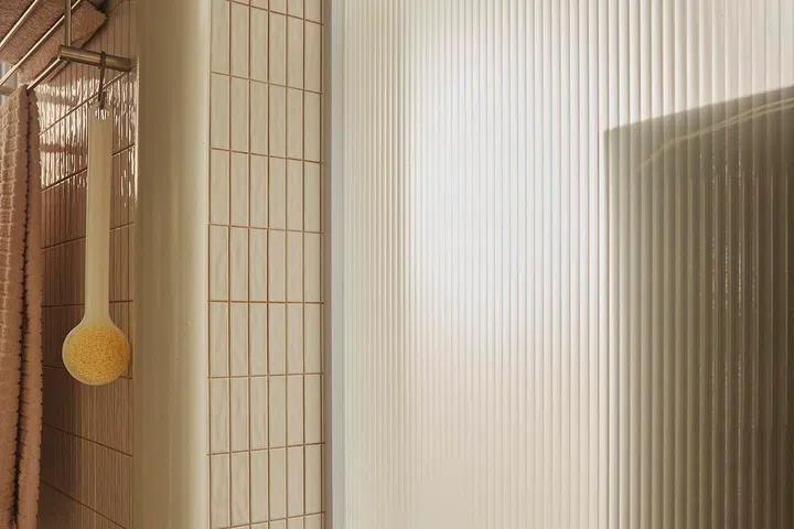 A fluted glass panel between the two bathrooms allows light to pass through while maintaining privacy, combining practicality with Ivan’s preferred old-school aesthetic.