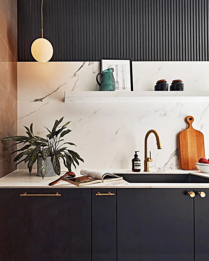Matte black cabinets with white marble-veined porcelain stone countertops now fill the kitchen.