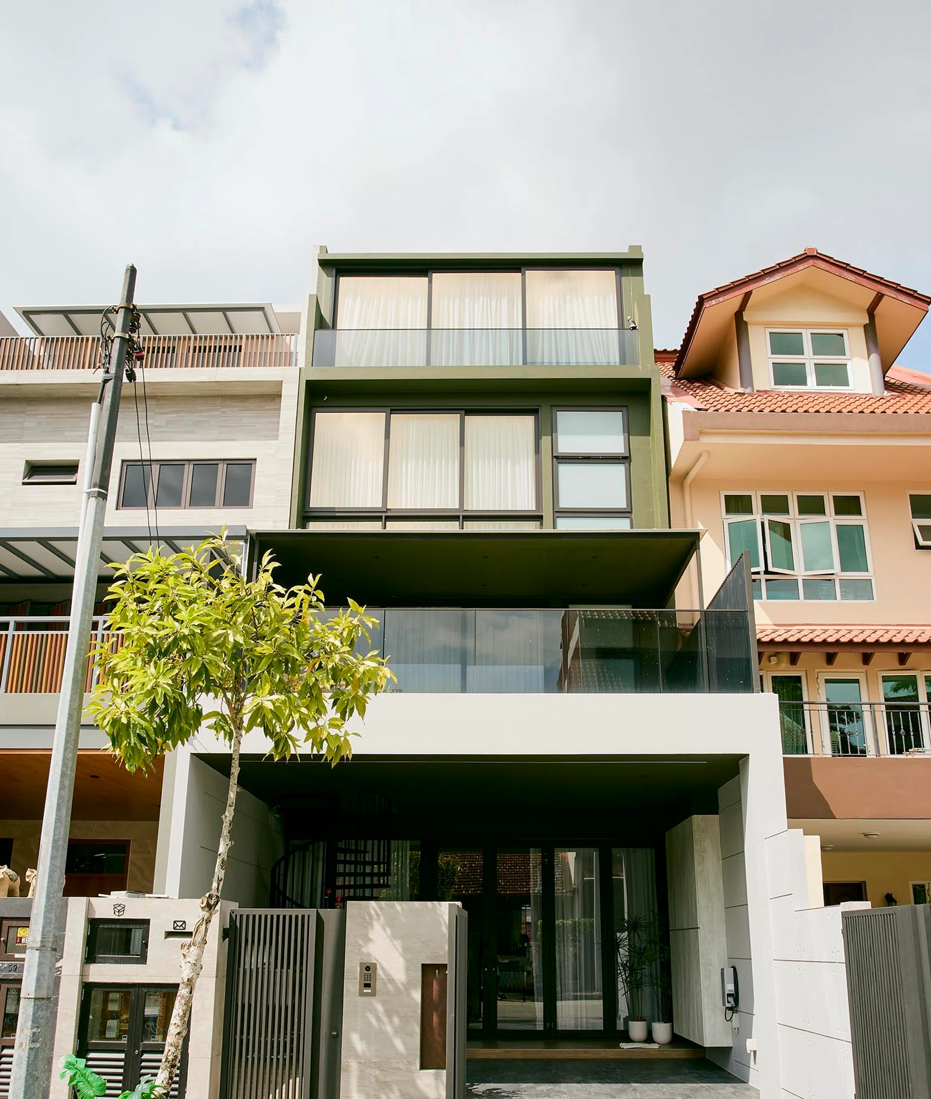 The rebuilt four-storey home asserts itself along the street with a boxy, glass-fronted form—a move its homeowners describe as “biting the bullet” after neighbouring houses began rebuilding.