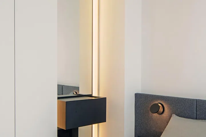 A mirrored panel in an apartment by Open Studio enlarges the feel of a small room.