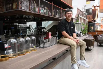 Hopscotch co-founder Roger Yip atop the bar counter he built himself, along with tabletops, design features and lighting.