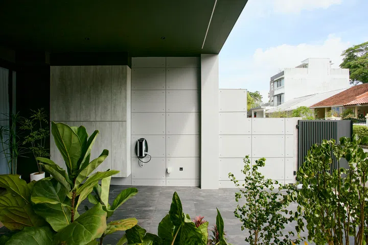 A sheltered front court introduces the home with a restrained palette of concrete, greenery and clean-lined surfaces, setting up a quieter transition from the street.