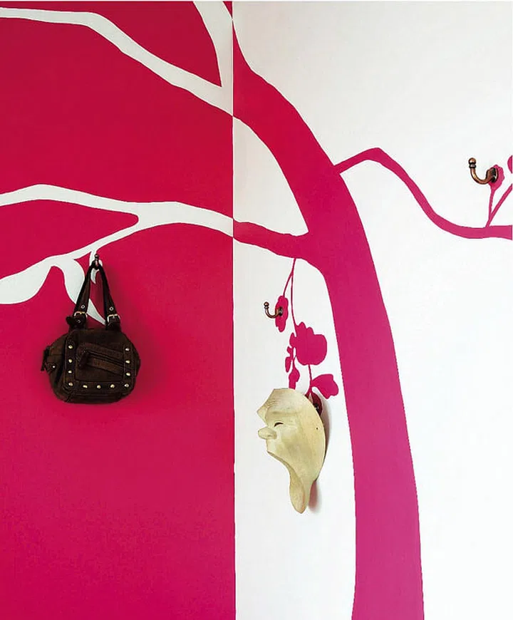 Handbags find their storage place on hooks fixed into the painted branches while adding to the mural decor.