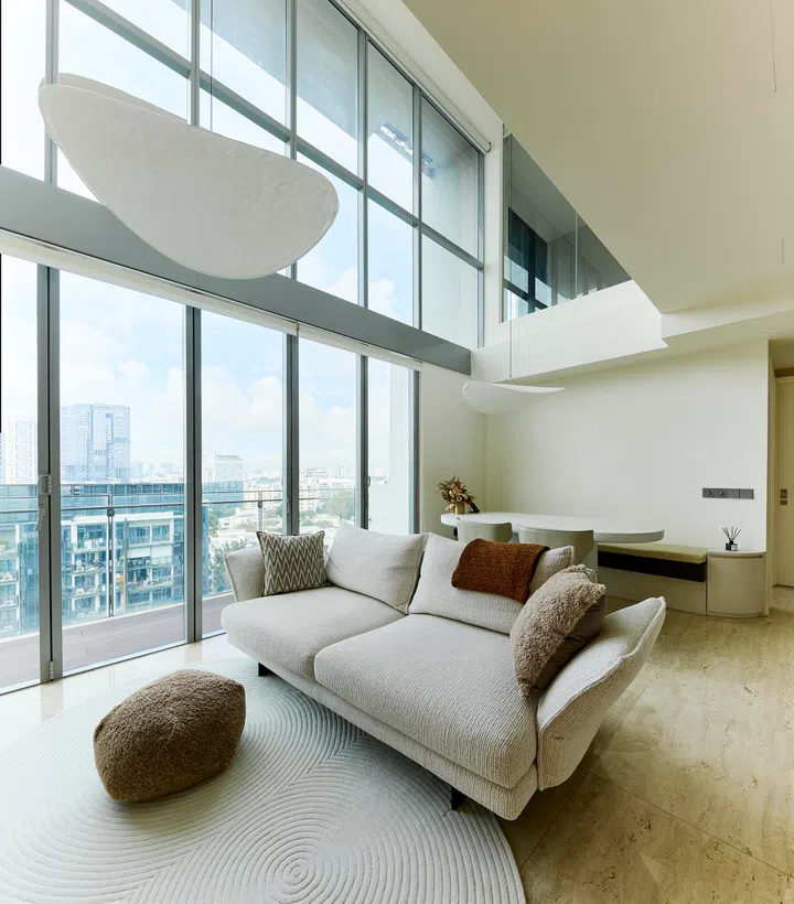 A seamless blend of elegance and warmth — the living room showcases a travertine feature wall, earthy tones, and double-volume windows that flood the duplex with natural light.