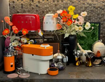 The Nespresso Vertuo Pop x Pantone Mandarin Orange coffee maker in a lounge setting.