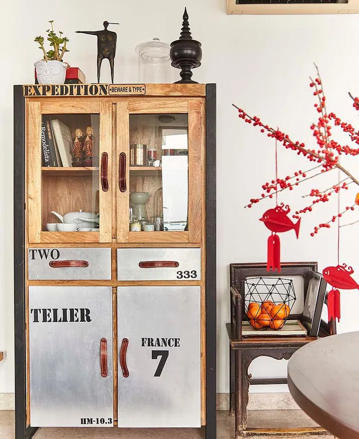 A wooden display cabinets for dinner ware and cups in interior stylist Mike Tan's home. A red pussy willow plant with red ribbons injects some Chinese New Year decor to his home.