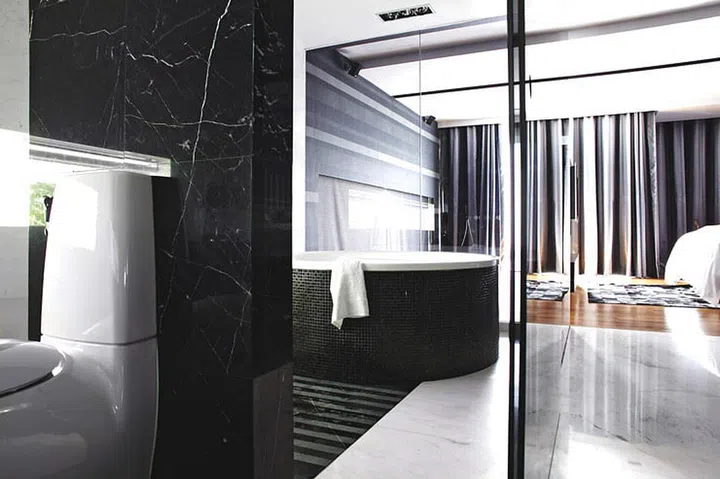 Glass panels allow a full view of the master bedroom from the bathtub. Interior design by Altered Interior