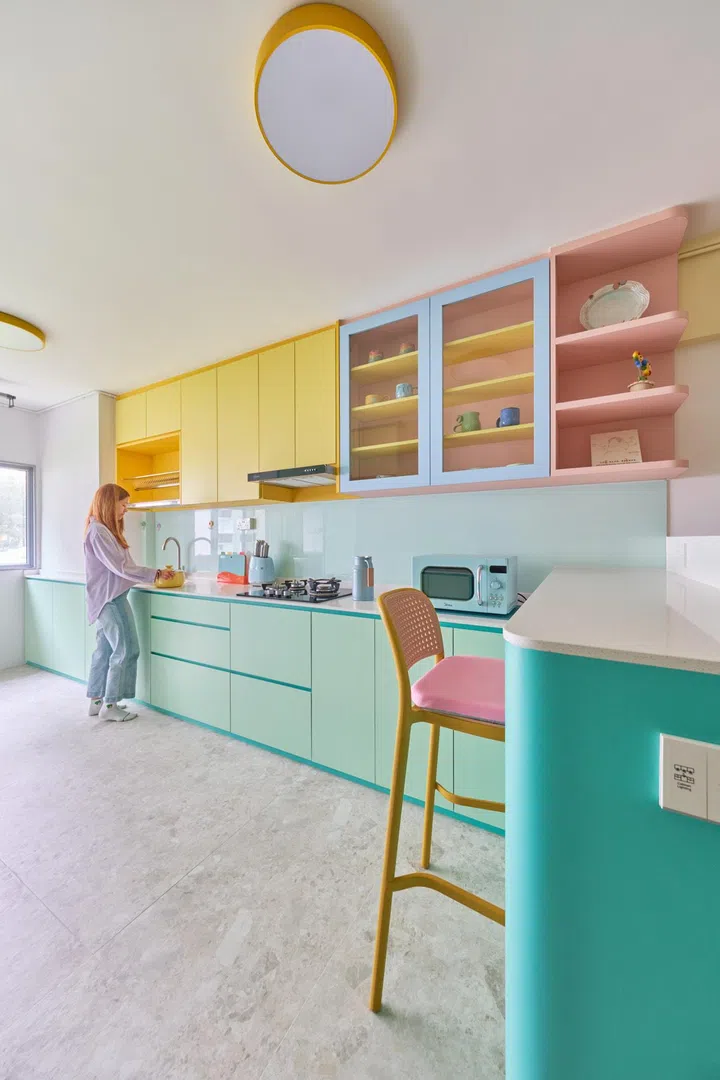 A long terrazzo-like countertop (Aurastone Quartz 1106 Nuvuo Snow) with light turquoise cupboards beneath flows from the dining nook until the end wall, with a window here allowing for natural light to flit off the soft shades chosen for the kitchen. 