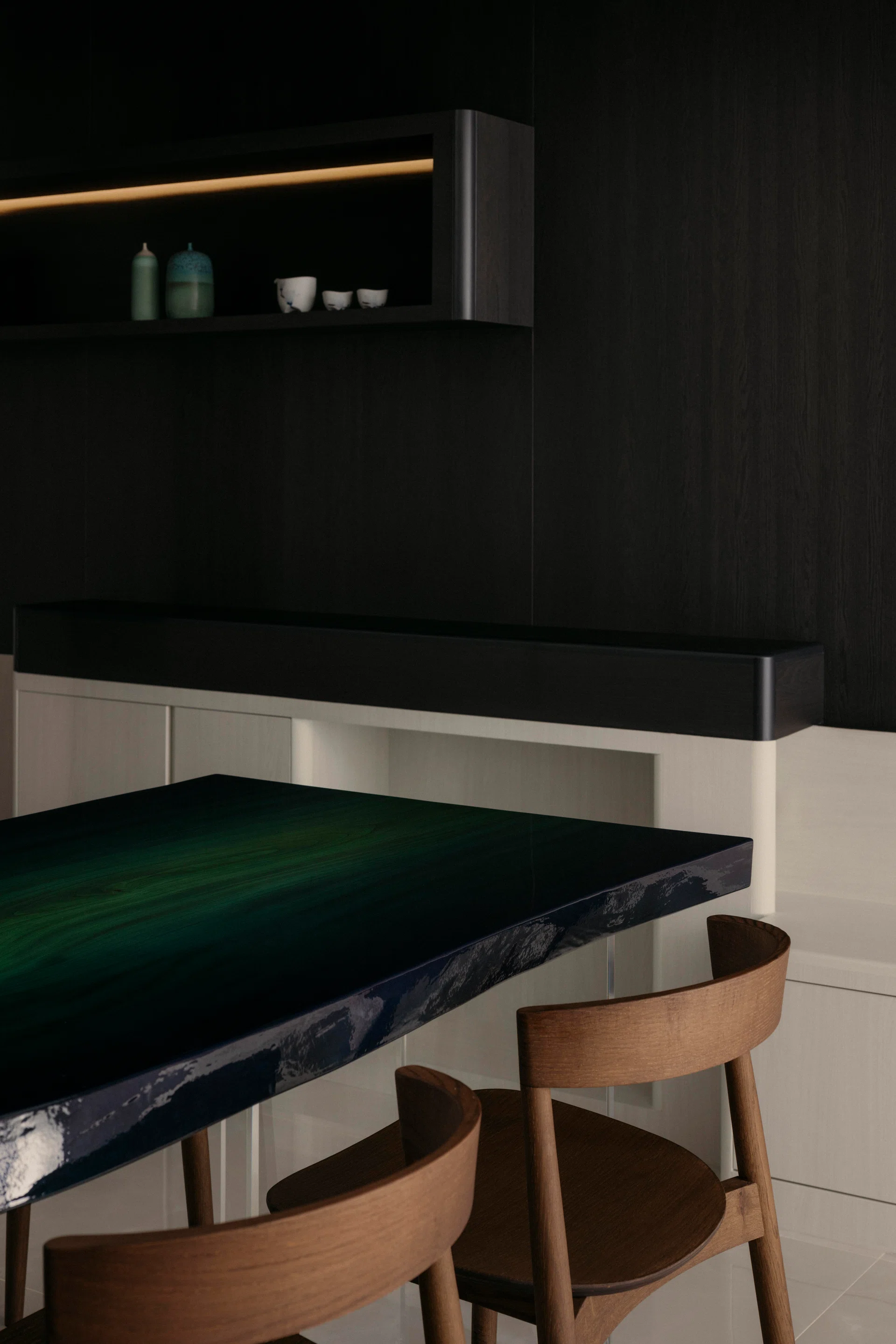 A custom dining table made from Japanese zelkova and dyed with natural indigo grounds the dining area against dark timber joinery.