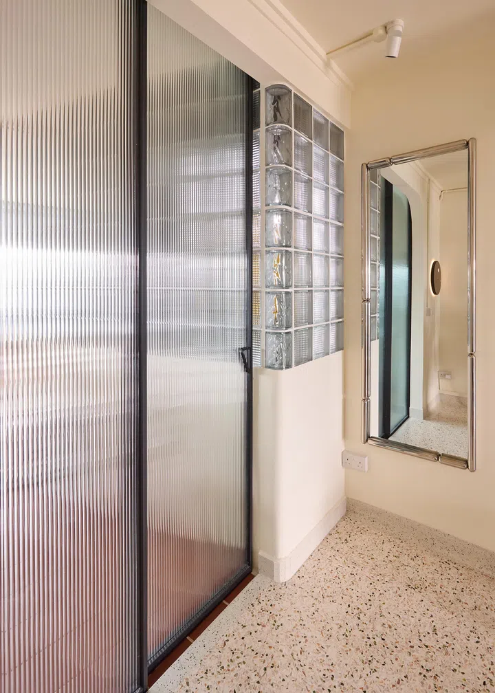 Fluted-glass doors and rounded brick corners complete the wall’s sculptural edge.
