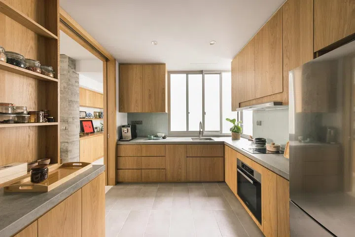 All wood kitchen cabinets matched with slate grey countertops and floor tiles in a 1,900 sq ft 3-bedroom condominium in Sentosa.