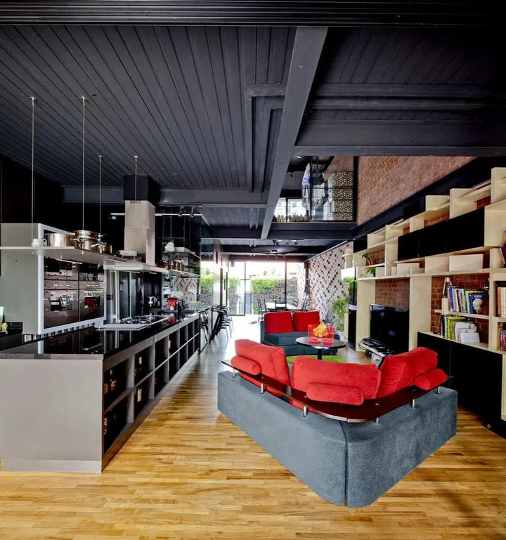 Made of a steel framework construction with lightweight metal composite, the raw and industrial look in the house is played down with the addition of timber flooring as well as furniture made of recycled wood.