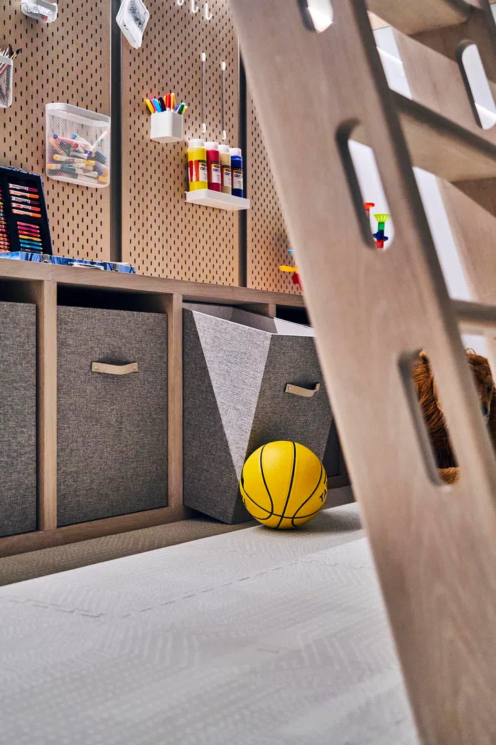 Bespoke storage walls with pegboards and bins keep toys and art supplies in order.