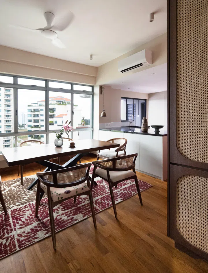 Opposite the dining table is a floor-to-ceiling rattan shoe cupboard with a wood teak laminate. The heavy green door next to the cupboard is the front door. 
