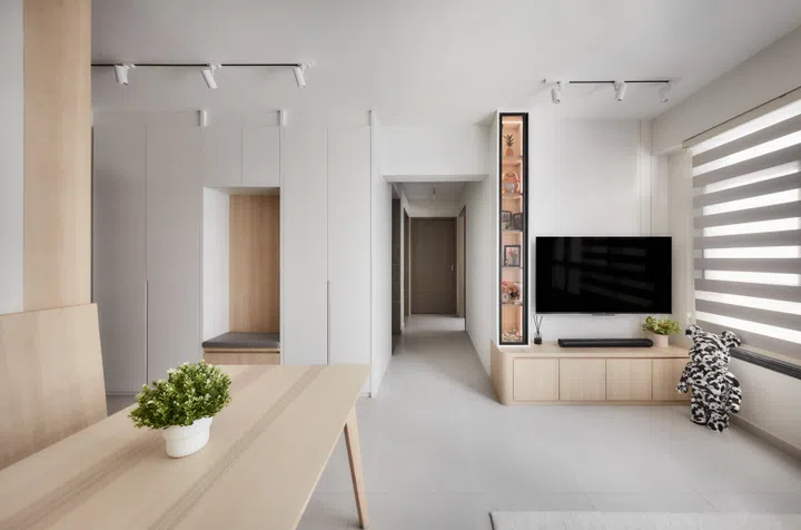 The compact living area is anchored by a slim TV wall and personal mementoes, giving the space warmth and character.