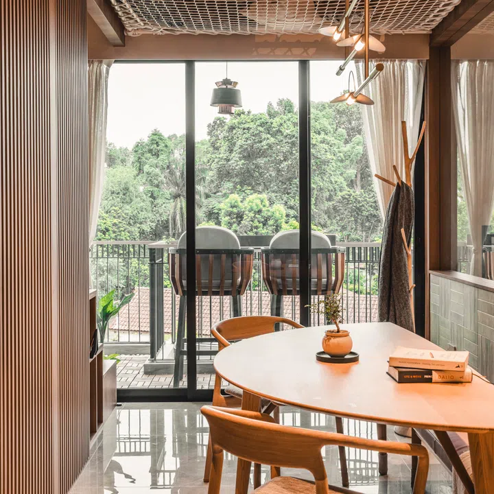 Full-height glazing at the balcony draws daylight deep into the dining area, demonstrating how orientation and window placement can make a compact home feel open and expansive.