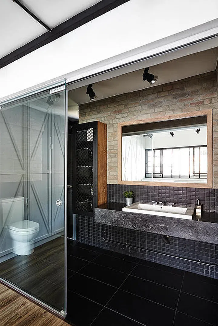 The master bathroom features a medley of materials; subway tiles, brick walls and mesh cabinet doors.