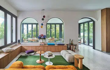 A light-filled dining room fit for a lavish dinner party or casual brunch by adding full-height, foldable glass doors and opening up the adjacent wall with three arched openings and a doorway.