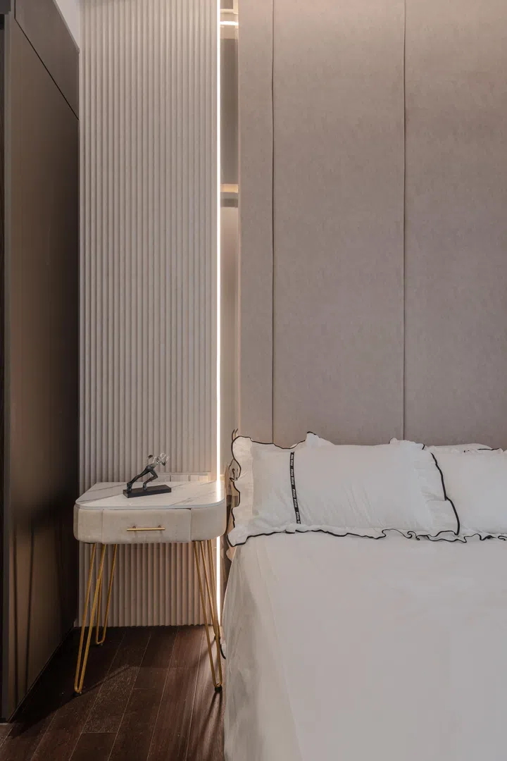 Tailored detailing, from the fluted wall treatment to the upholstered headboard, gives the room a quiet sense of luxury without unnecessary embellishment.