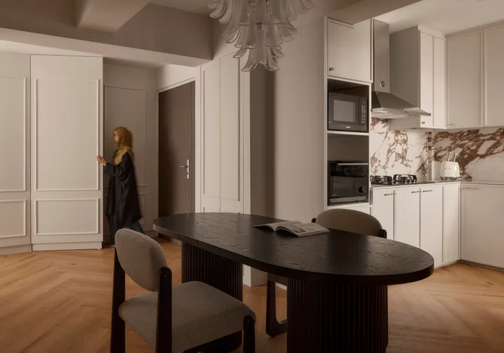 Homeowner Trisha pushes open a concealed door along a wainscotting wall in her 4-room HDB BTO (1,004 sq ft) in Bishan, designed by RENOSTUD.IO.