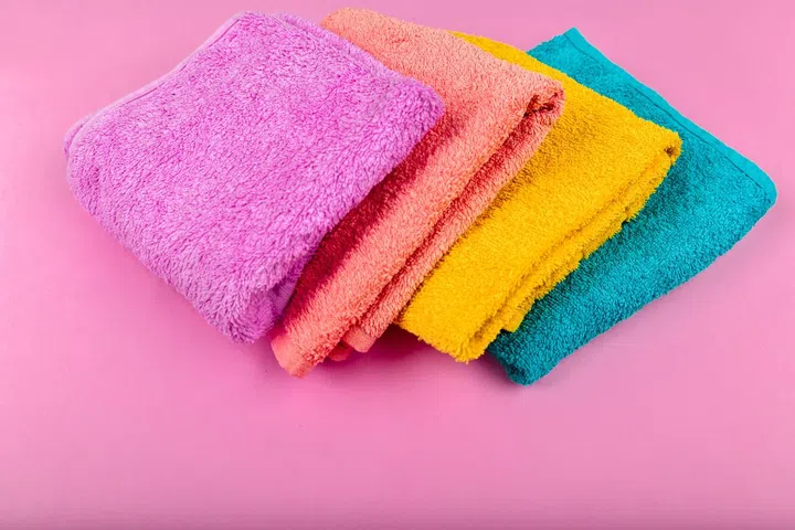 Multi-colored towels on a pink background. Pink, beige, yellow and blue flower towels. Place for writing. House order