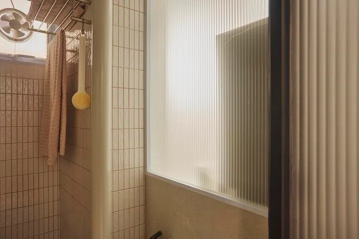 Fluted glass appears throughout the flat, from room dividers to bathroom doors, creating visual continuity across the home.