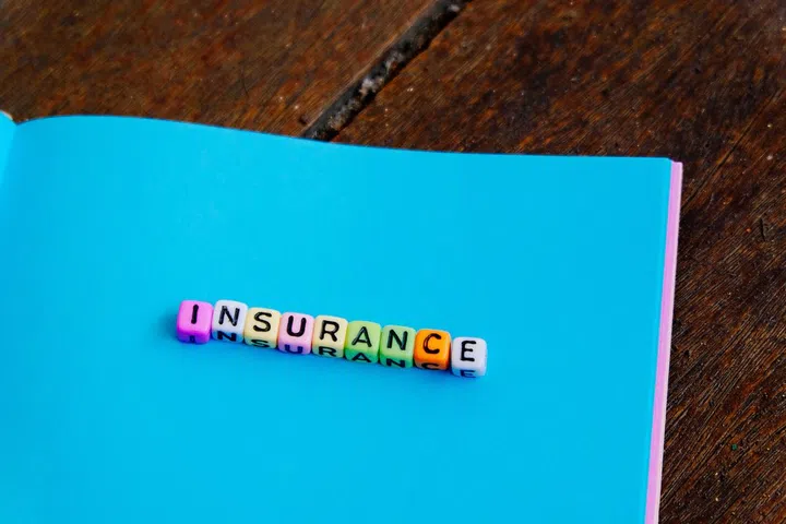 conceptual image with INSURANCE word block on note pad over wooden background.