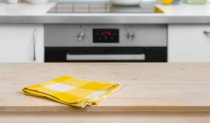 Wooden table with yellow napkin on kitchen background