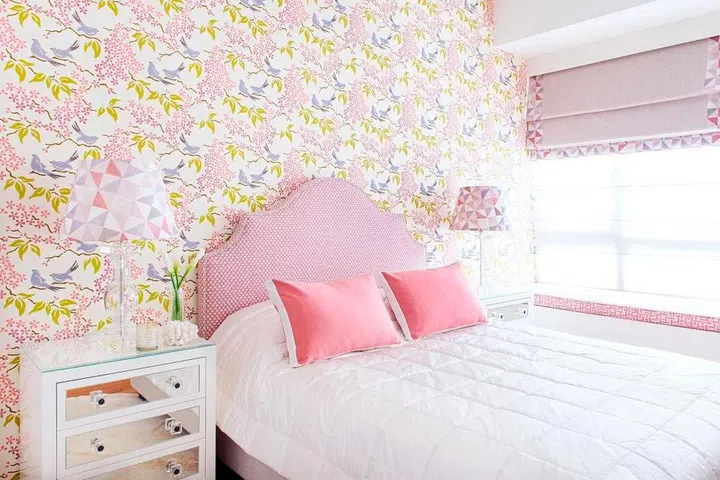 A pretty wallpaper pattern sets the feminine tone for this bedroom, with the colour of the padded fabric headboard taken from it. White bedlinen balances out the pink. Design: E&A Interiors