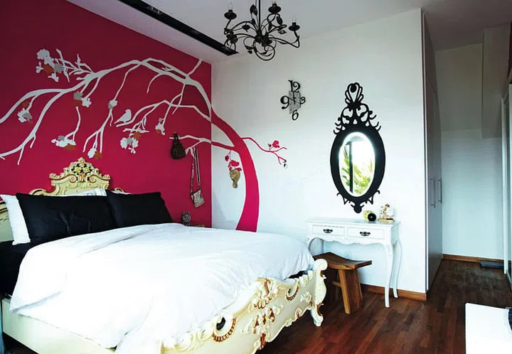 Andre painted a charming tree mural on a pink wall in another bedroom. This tree, the backdrop of an elaborately carved Victorian-style bed frame, comes complete with clusters of painted flowers and perched birds.