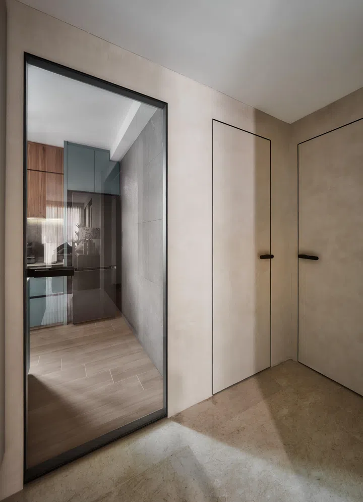 Concealed storage blends into wallpapered panels, while a checkered glass sliding door leads to the kitchen — keeping spaces bright yet private.