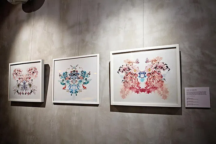 A series of three framed artworks hanging on a concrete panel wall. Photo by Mad Nest Restaurant