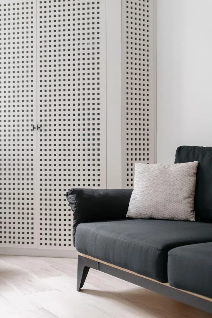 Black and white pillows on sofa in modern living room interior with wooden wardrobe