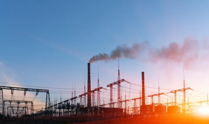 Distribution electric substation with power lines and transformers, at sunset