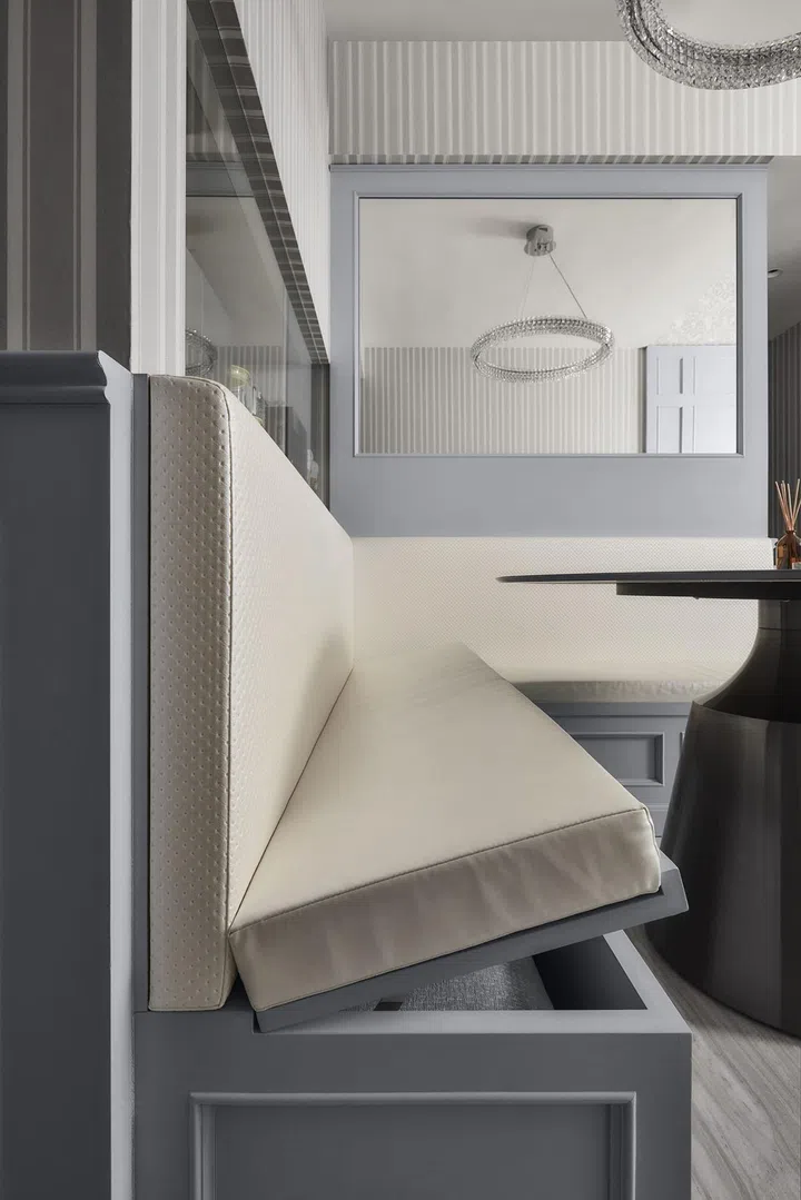 A mirror above the cushioned dining bench with storage.