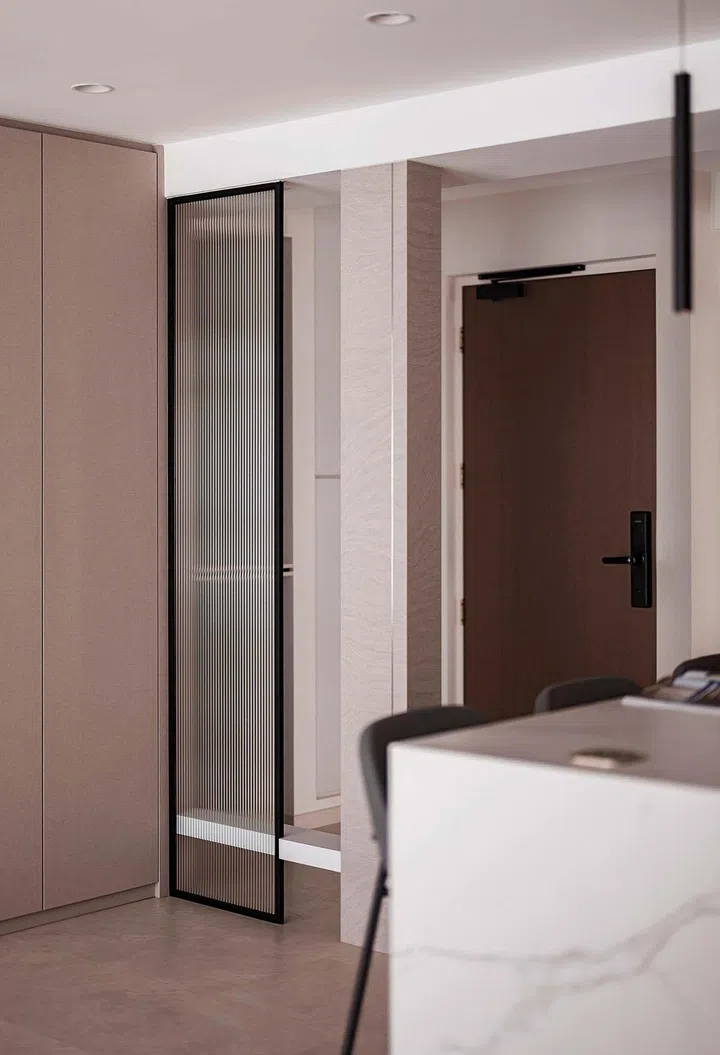 A reeded glass panel separates the entrance foyer from the living area and screens the latter from the corridor outside.
