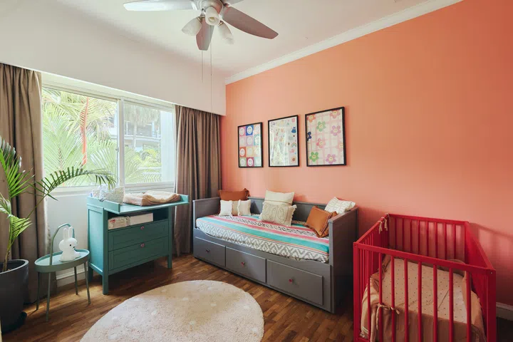 A  coral feature wall, repainted furniture and cheerful artwork create a playful yet calm space designed to evolve  alongside the family’s youngest daughter.