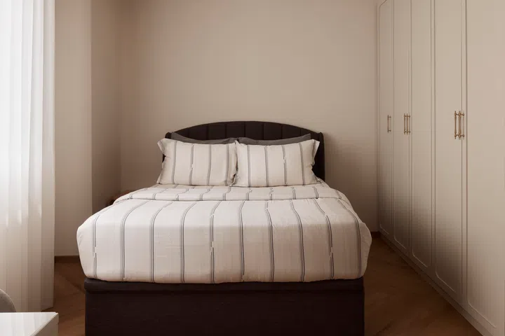 Soft neutrals, classic shaker-style wardrobe detailing and warm timber flooring continue the home’s minimalist farmhouse palette, giving the bedroom a quiet, restful character.