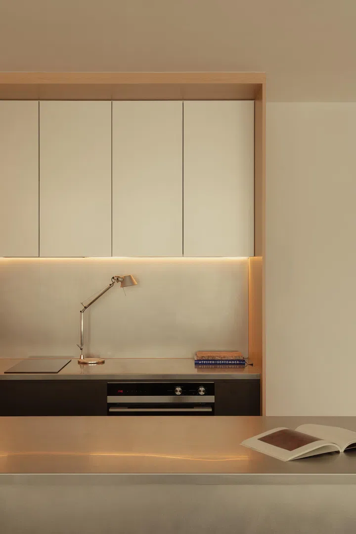 A brushed steel countertop reflects soft light through the day, echoing the building’s glass façades beyond.