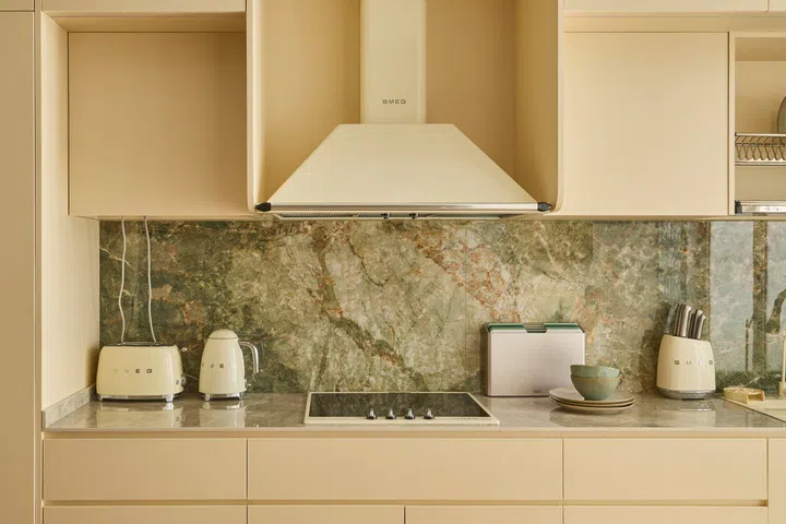A veined stone backsplash introduces subtle variation, pairing with warm-toned cabinetry to soften the overall composition.