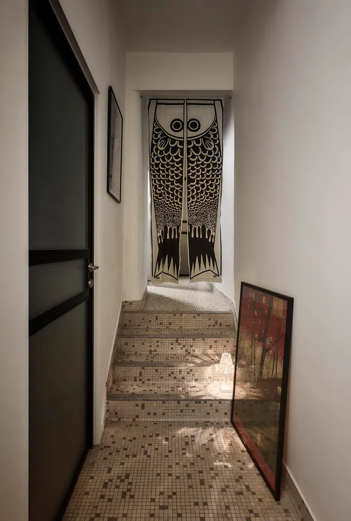 A quiet passageway lined with original mosaic flooring and personal artwork captures the spirit of the home—layered over time, shaped by use, and comfortably lived in.