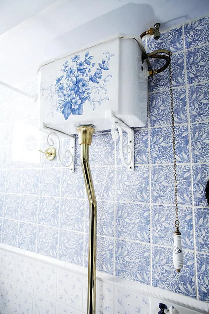 White ceramic toilet, cistern, and bidet with blue traditional old English floral patterns cost $17,000. All solid brass features plated in 18K gold.