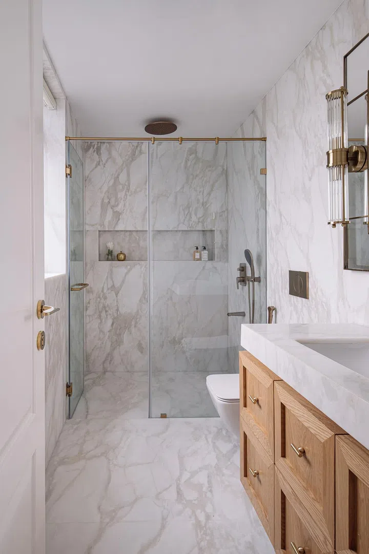 All white marble-clad master bathroom in this 2-bedroom apartment in Parsi, Mumbai.