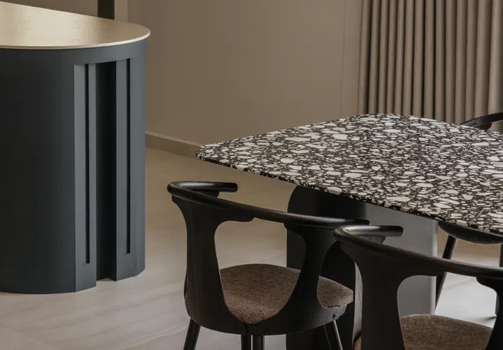 A closer look at the dining setting, where a dark textured tabletop and sculptural chairs ground the space.