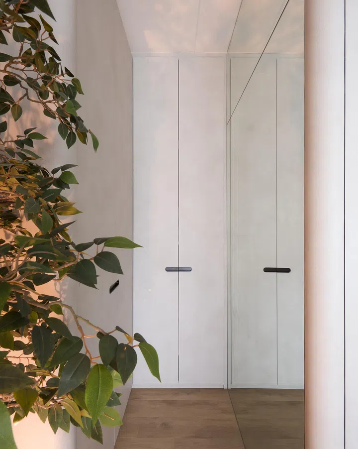 An artificial tree surrounded by pebbles, softly illuminated, creating an art-like presence, with discreet storage space tucked behind it.