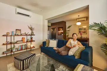 A social service professional in her 30s poses for a photograph in the living room of her 3-room HDB flat in Potong Pasir (797 sq ft), designed by TALA Design + LLP.